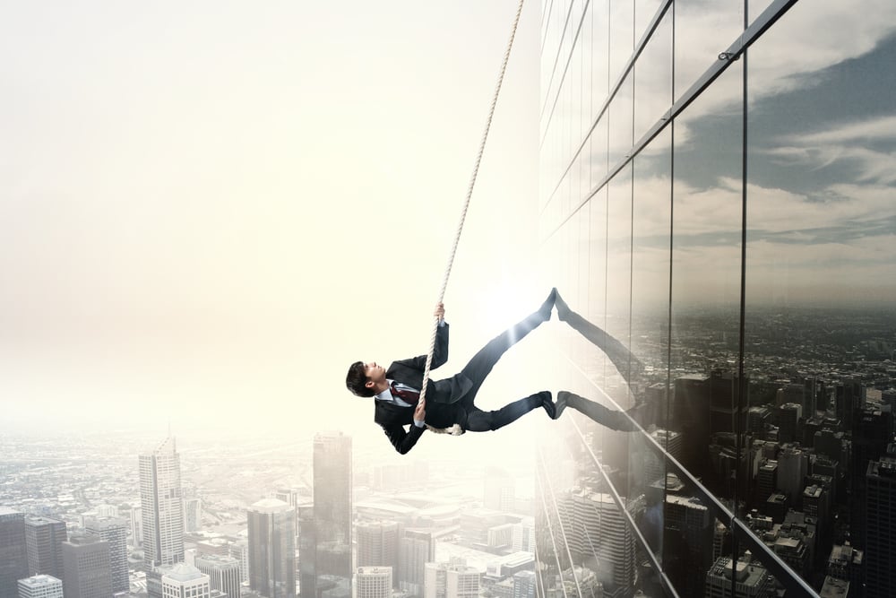 Determined businessman climbing building with help of rope